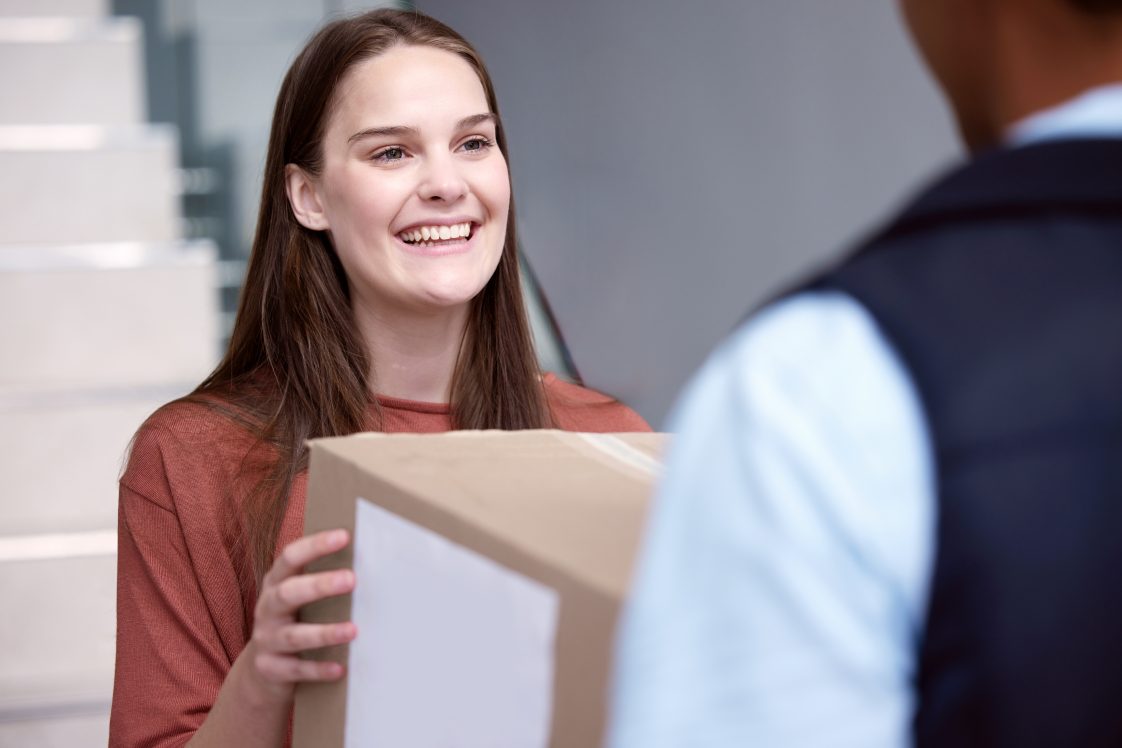 smiling woman receiving package from carrier at door