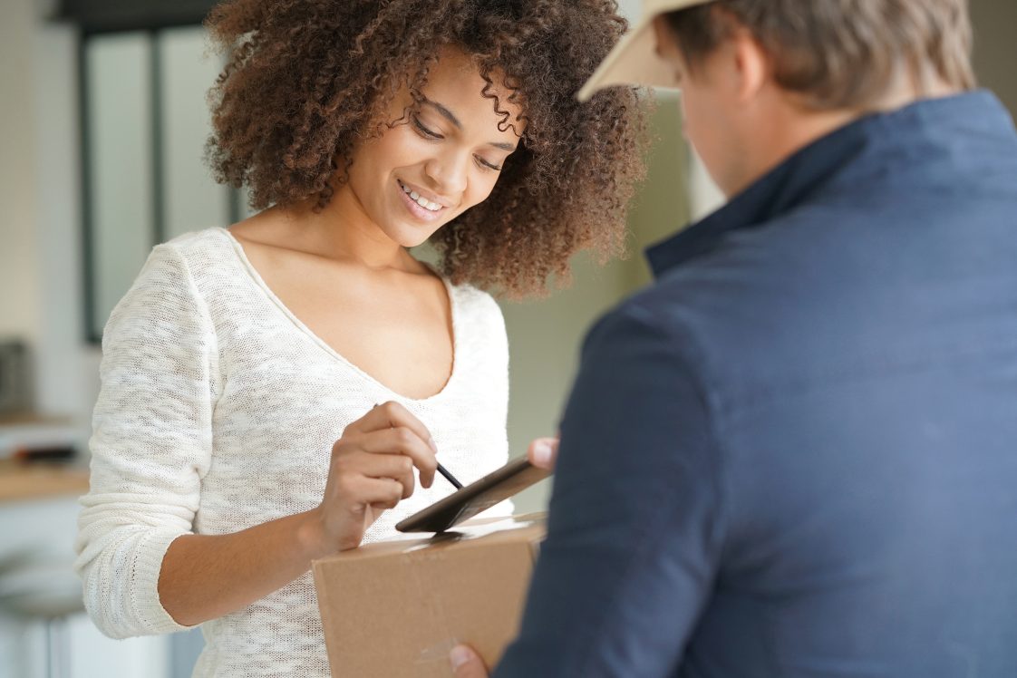 woman signing for package at door