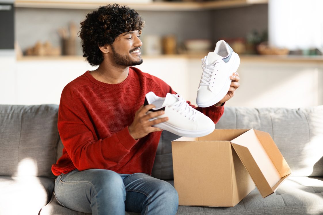 happy man opening up a package of shoes