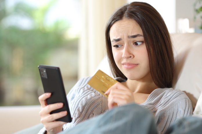 woman on phone with credit card with confused look on face