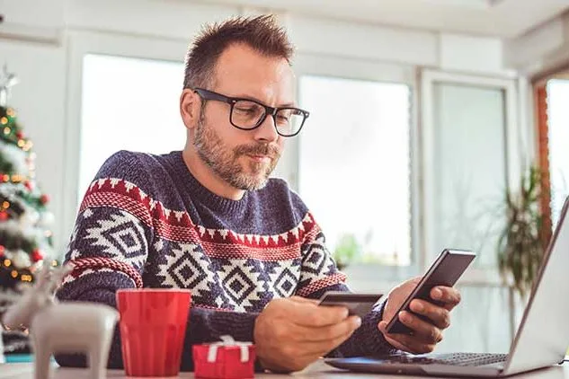 man holiday shopping on phone and computer