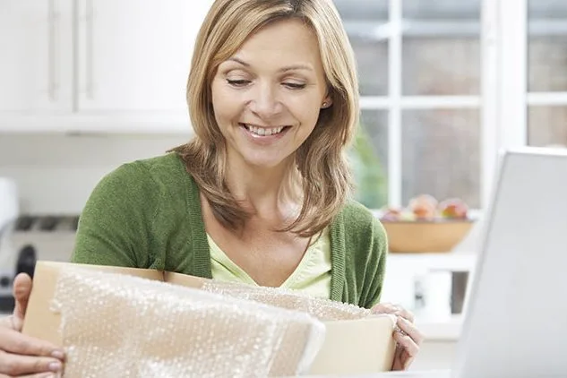 woman opening package in front of laptop