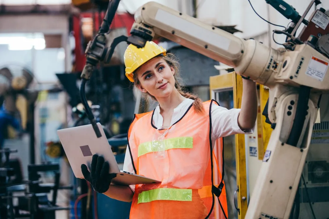 woman in fulfillment center working with a robot picking arm