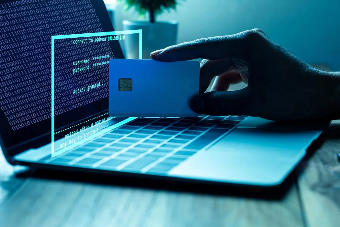 person holding credit card in front of laptop with computer code on it